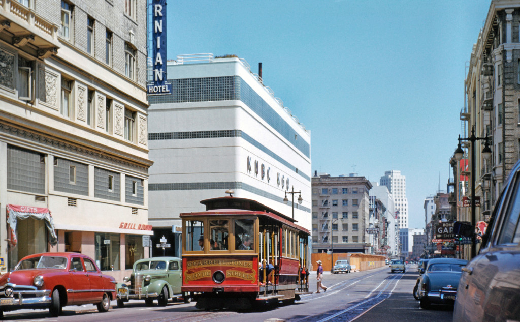 One vanishing institution passes another on May 2, 1954. Two weeks away from the end of the O'Farrell, Jones & Hyde line, Cable Car No. 57 rumbles west on O'Farrell Street past the Art Deco NBC Radio building. (That hole in the ground beyond is the site of the huge Downtown Center Garage, a big reason for pressure to make O'Farrell one-way.) NBC had been the dominant US radio network in the 1930s and 40s (actually two networks, the Red and the Blue, which was spun off to become ABC). In that era, station call letters were important marks of prestige. NBC's two powerful stations here were originally called KPO and KGO, but the company redesignated KPO with the company initials, sending the message that NBC considered San Francisco the most important city west of the Mississippi (where stations' first call letter was almost always 'K'. WNBC was in New York City, then as now corporate headquarters). The building at 420 Taylor Street housed state-of-the-art NBC studios, with an artistic tribute to a goddess of the airwaves over the front door (still there today). But network radio was on the wane by 1954 as television took over America's living rooms. Local personalities were coming to the fore in radio, including San Francisco, where the hottest was Don Sherwood, who had recently joined KSFO. NBC later assigned the prestigious 'KNBC' designation to its television station in...Los Angeles, renaming its once-dominant San Francisco radio station 'KNBR'. The radio game in San Francisco has changed repeatedly since this picture was taken, but Car No. 57 still rolls on every day...on the California Cable line, right past the site of Sherwood's KSFO studio in the Fairmont Hotel. Walt Vielbaum photo.